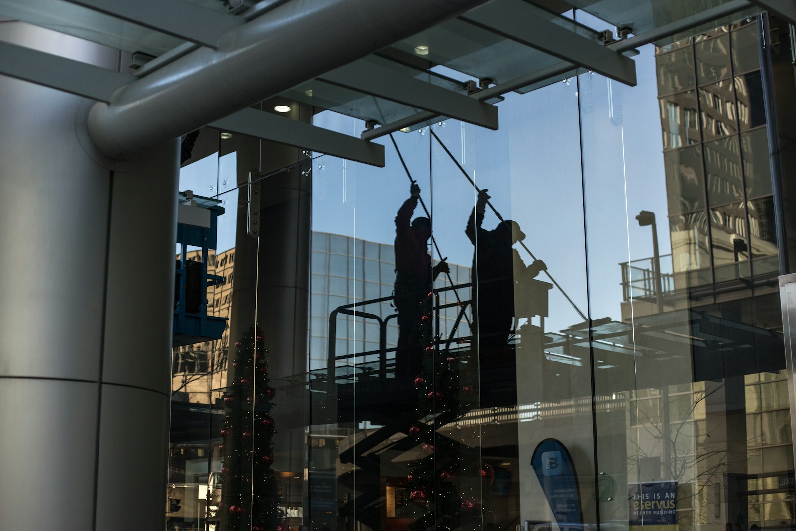 Photo by Priscilla Du Preez 🇨🇦 utility man standing in scissor platform cleaning glass window